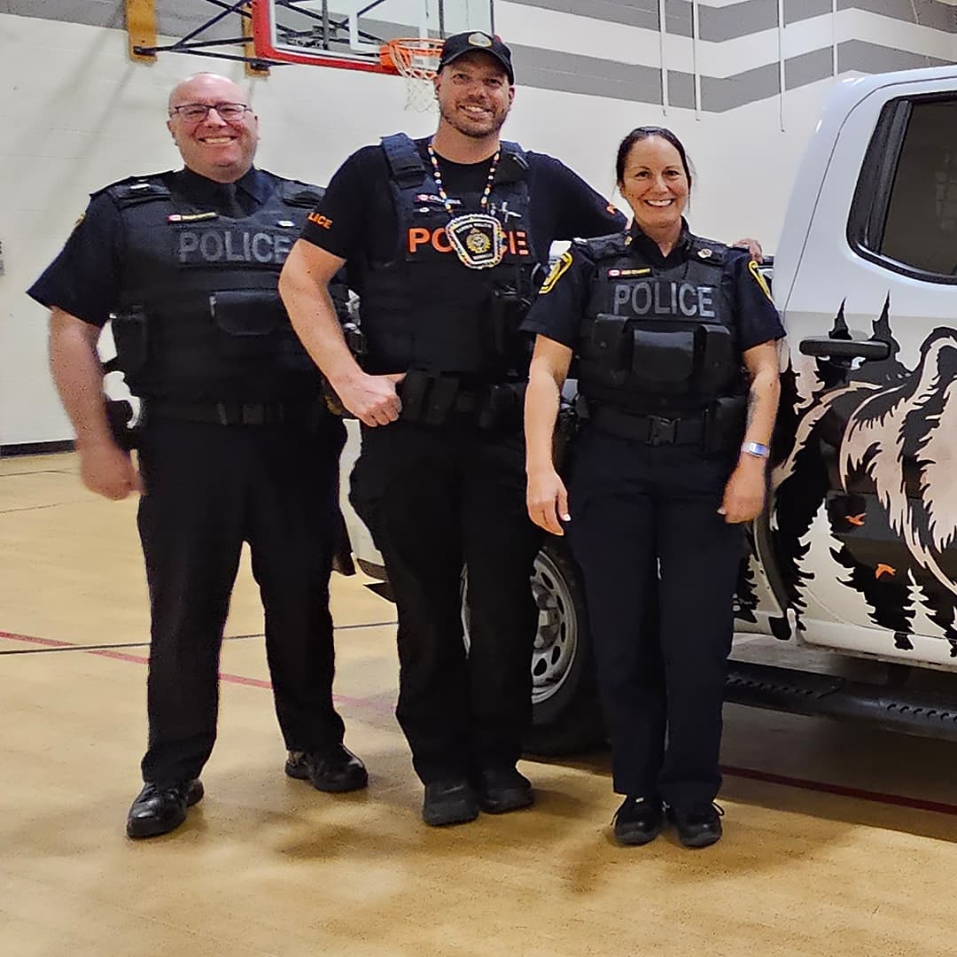 police officers standing in front of Aamjiwnaang First Nation police vehicle