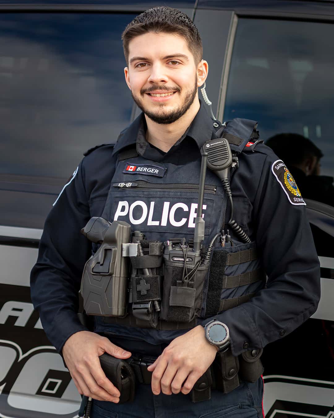police constable standing in from of Sarnia Police Service cruiser