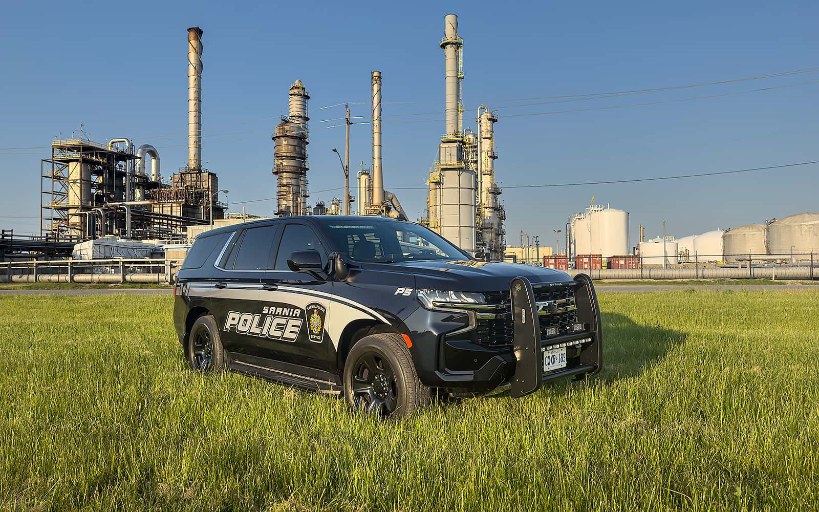 Sarnia police vehicle in grass field in front of chemical plant